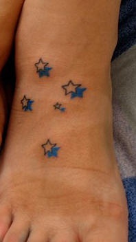 el tatuaje pequeño de unas estrellas con su sombra azulhecho en el pie