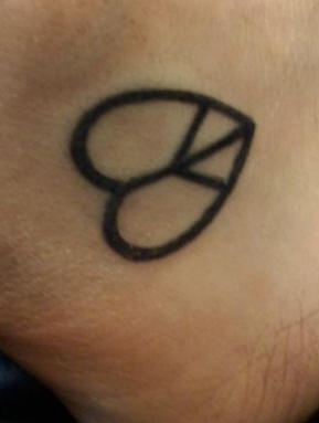 el tatuaje minimalista del simbolo de paz en forma de corazon