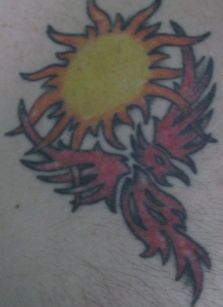 el tatuaje tribal de la ave magica fenix de color rojo con el sol