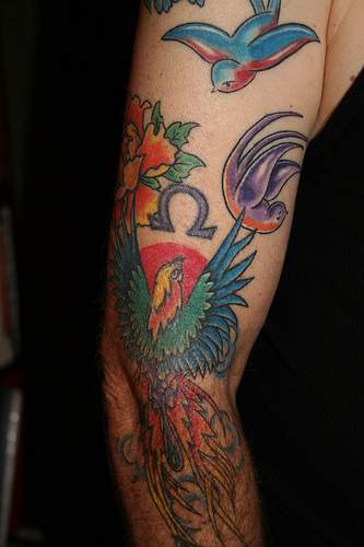 el tatuaje grande colorado de varias aves incluyendo ave fenix hecho en el brazo