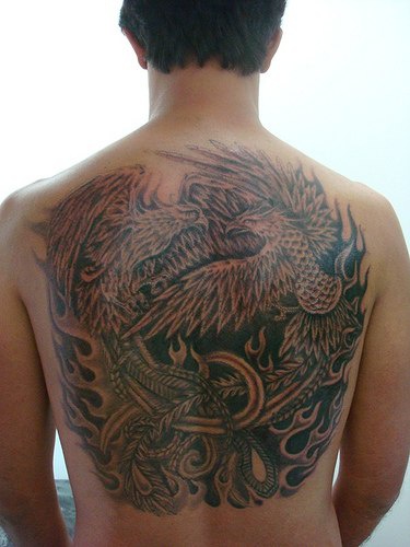 el tatusje grande detallado de las dos aves fenix en las llamas de fuego hecho en tinta negra en la espalda