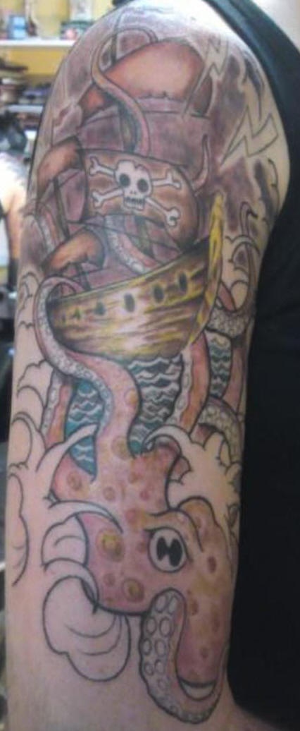 el tatuaje tematico de piratas con un barco, calaveras,un pulpo en el mar hecho en color en el brazo