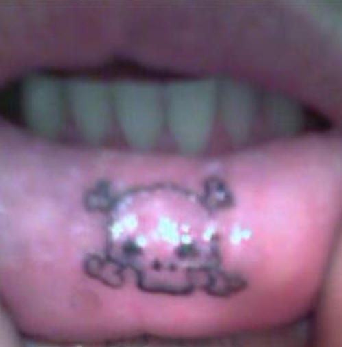 el tatuaje pequeño en el labio con una calavera pirata