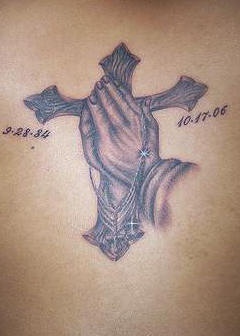 el tatuaje conmemorativo de una cruz y dos manos en oracion con fechas de la vida hecho en color negro