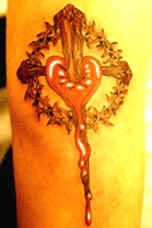 el tatuaje de cruz y un corazon sangrando hecho en color