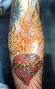 el tatuaje del corazon sagrado con una cruz en las llamas de fuego