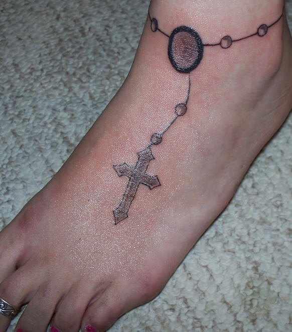 Tatuaje descolorido en el pie, pulsera con un cruz