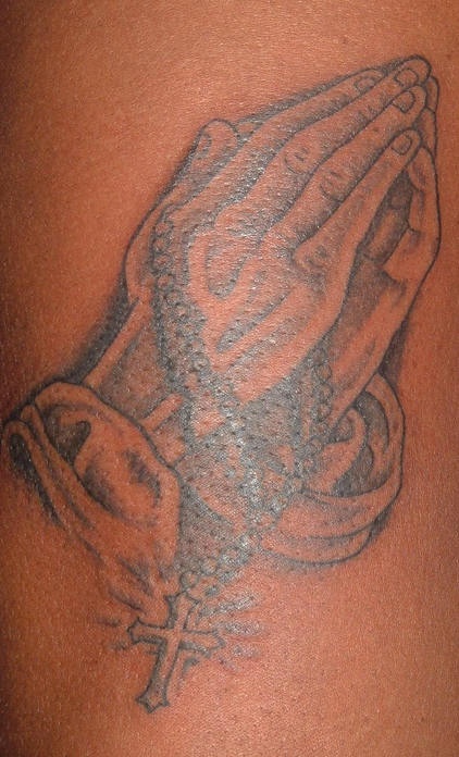 Rosario e mani mentre preghiera tatuaggio