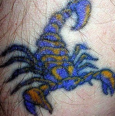 Pequeño escorpio tatuaje en tinta azul y amarilla
