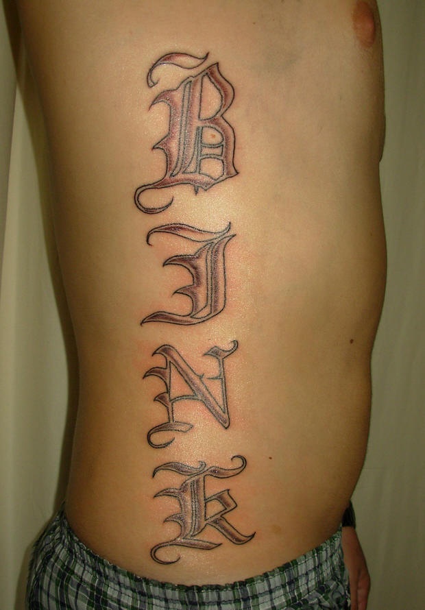 Le tatouage sur le flanc avec une inscription en style intéressant