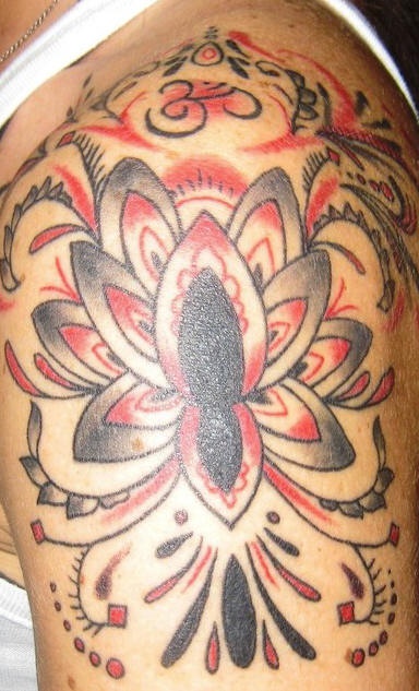 Tatuaje en hombro con flor y ornamentación semi colorados