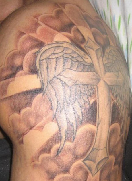 Tatuaje en hombro con cruz, alas entre las nubes