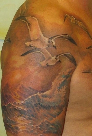 Le tatouage de l"épaule avec des belles mouettes volants au dessus de la mer