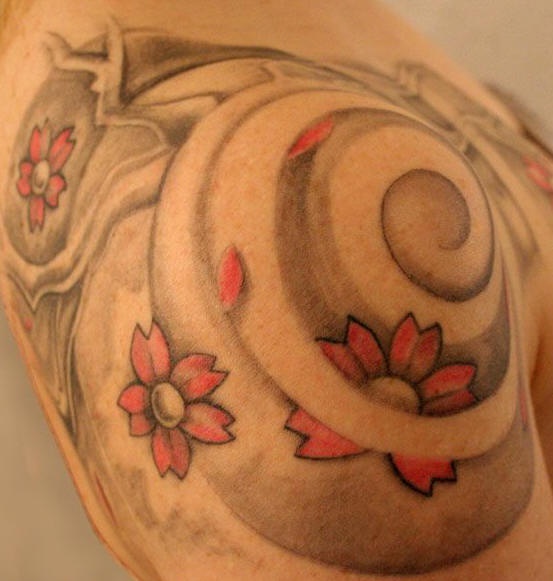 Tatuaggio non colorato sul deltoide i fiori nel vortice