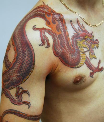Tatuaggio grande colorato sul deltoide e sul petto il dragone terribile color fuoco