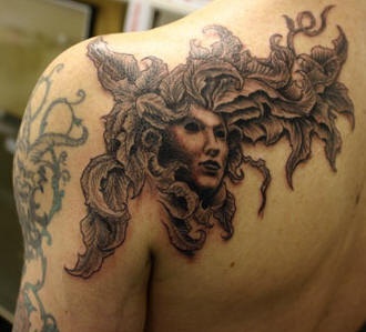 Le tatouage de l"épaule avec un visage sans émotion dans une plante poussant