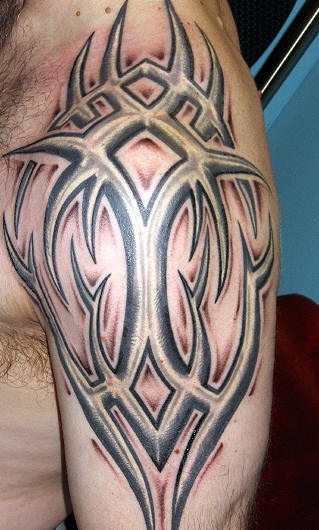 Tatuaggio grande non colorato sul deltoide il disegno in stile tribale