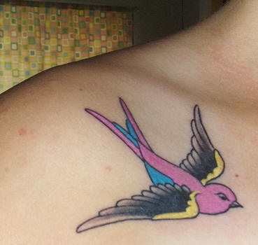 Le tatouage de l"épaule avec une hirondelle multicolore en vol