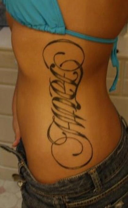 Tatuaggio sul fianco la scritta a lettere calligrafiche