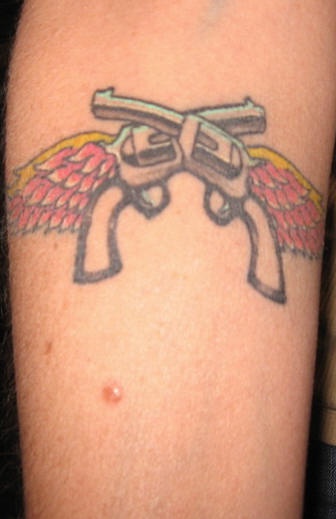 Tatuaje dos pistolas con las alas en el brazo