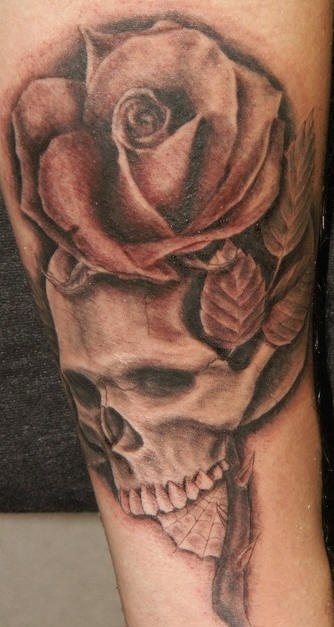 Muy realístico tatuaje de calavera con una rosa grande