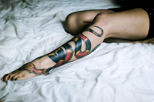 Un serpent rouge et noir le tatouage sur la jambe