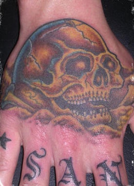 Tatuaje en la mano, cráneo amarillo que se ríe