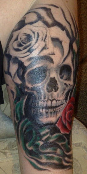 Tatuaje en la pierna, cráneo con dos rosas, blanca y roja