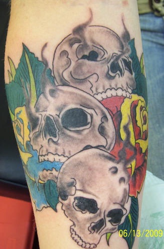 Three skulls and roses coloured tattoo