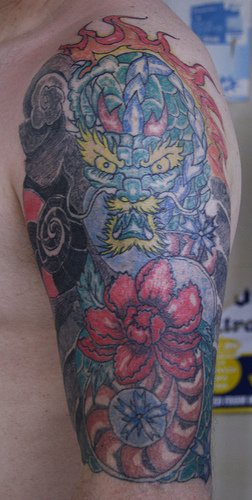 Magic dragon and flowers sleeve tattoo