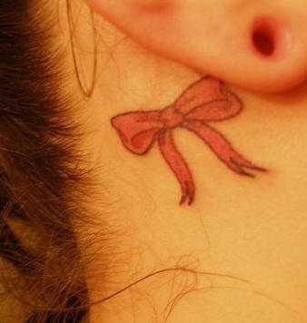 Red bow tattoo behind ear