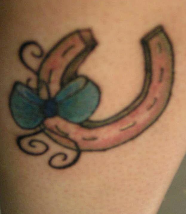 Un petit fer à cheval aves le tatouage de nœud papillon bleu