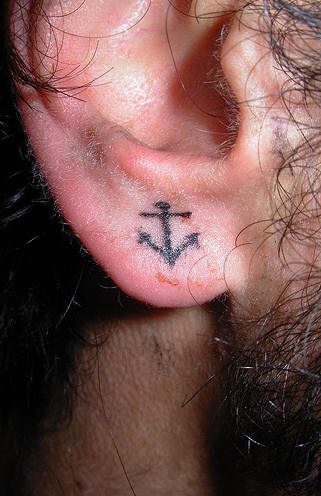Kleiner schwarzer Anker Tattoo am Ohrläppchen