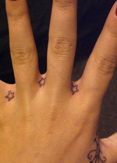 Small stars tattoos between fingers