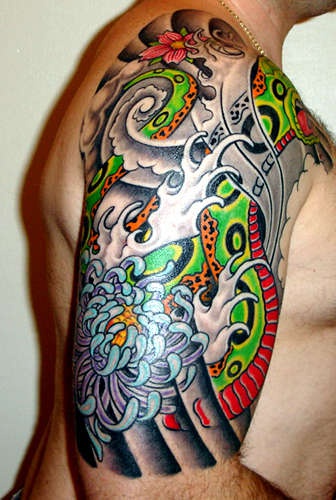 Tatuaggio colorato sul deltoide il serpente verde & le onde