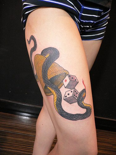 Tattoo mit Schlange und Würfeln am Schenkel