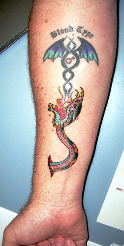 Tatuaggio colorato sul braccio il serpente & il disegno delle ali & &quotBLOOD TYPE"