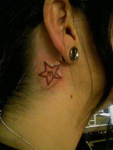 Kleines Tattoo mit Stern hinter Ohr