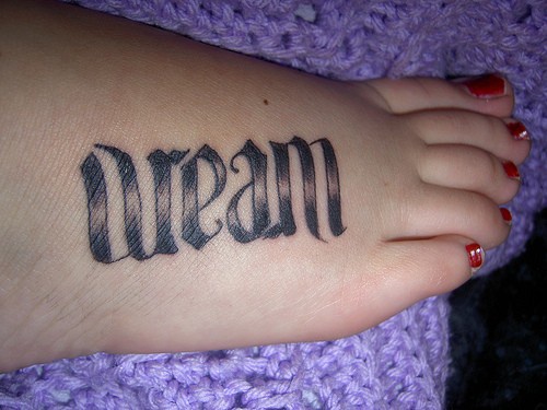 Tatuaje en el pie, la inscripción visible, caracteres gruesos, sueño