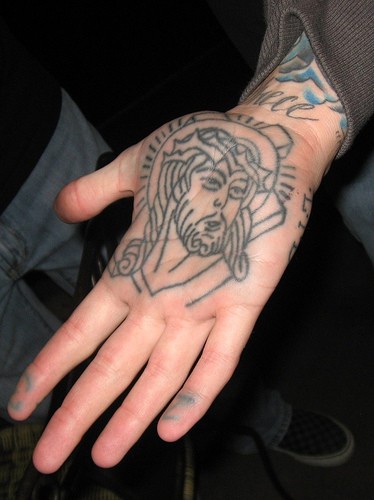 Realistisches nichtfarbiges Tattoo von sprechendem Jesus an der Hand