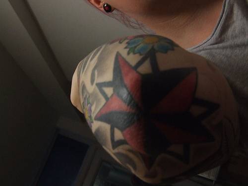 Tatuaje en color en el codo estrella con otros elementos