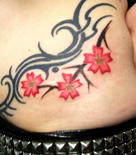 Tatuaje en la cadera, flores en la rama y líneas diferentes