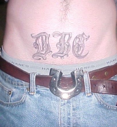 Stomach tattoo, three very designed letters