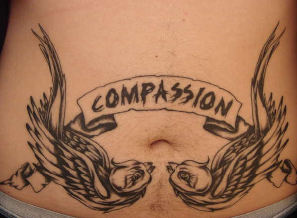 Tatuaggio sulla pancia la scritta  &quotCOMPASSION" tra gli uccelli