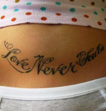 Tatuaggio sulla pancia la scritta calligrafica &quotLOVE NEVER FAILS"