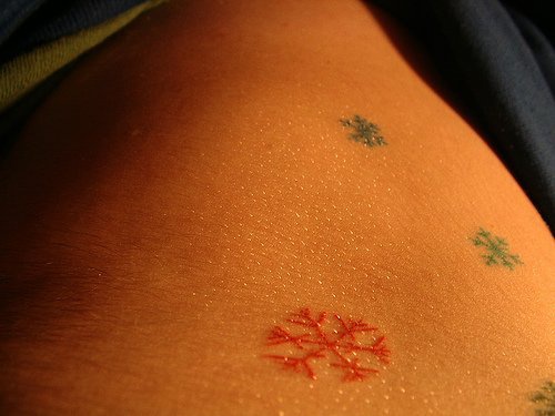 Stomach tattoo, little colourful snowflakes flying