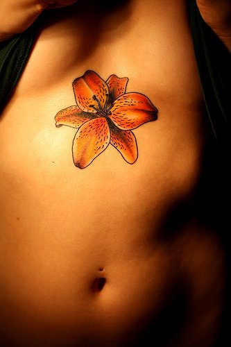 Le tatouage sur l&quotestomac avec une belle orchidée orange