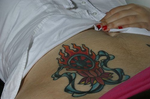 Stomach tattoo, blue wheel on the fire, decorated