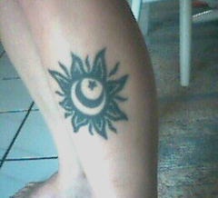 Black ink sun and moon tattoo on leg