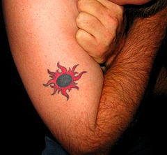 Black flaming sun tattoo on arm